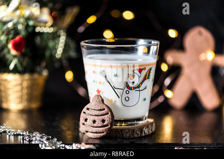 Pallina di natale a forma di biscotto e un bicchiere di latte per Santa Claus, vicino, indoor. Concetto di vacanza fotografia macro Foto Stock