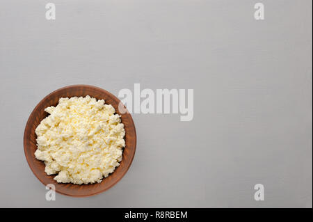 Immagine di fresco formaggio cottage con lieve aroma e liscia in una ciotola sul tavolo di legno. Mangiare sano concetto.la proteina del latte.Flat laici. Foto Stock