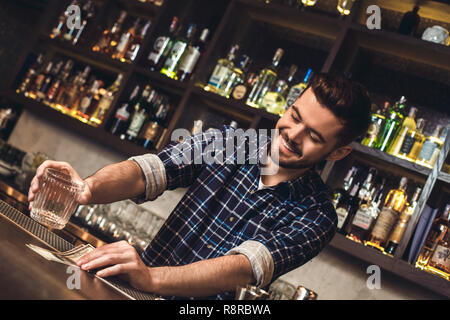 Giovane barista permanente al banco bar in vetro di contenimento di prendere il pagamento per bere allegro Foto Stock