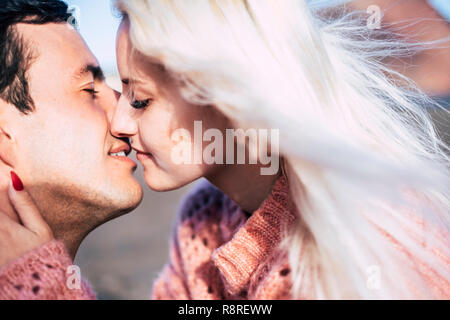 Closeup Ritratto di giovane bella attraente coppia caucasica baciare sotto il sole in spazi esterni - amore e kiss giovani concetto millenario Foto Stock