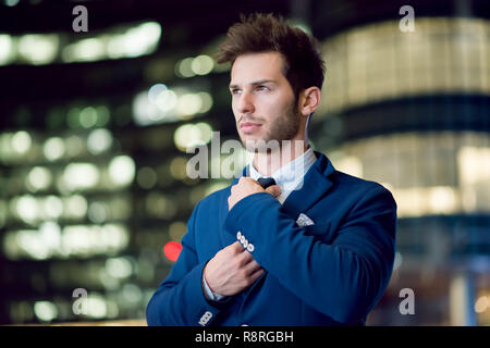Ritratto di un imprenditore sorridente adegua la sua cravatta Foto Stock