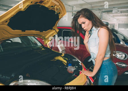 Il giovane dai capelli scuri esaminando donna auto presso la concessionaria e di compiere la propria scelta. Foto Stock