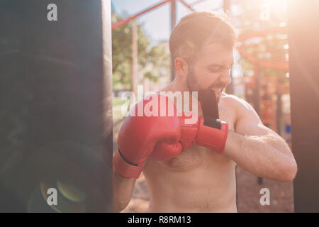 Giovane uomo boxe allenamento. Boxer esercizio atletico Concetto di inscatolamento. boxer punch mano da sacco da boxe. Foto Stock