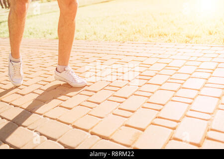 Atletica Giovane uomo in esecuzione in natura. Uno stile di vita sano. Barbuto dai capelli nero sportivo è in esecuzione su strada - tramonto back lit Foto Stock