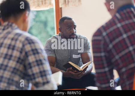 Attento giovane con la bibbia in gruppo di preghiera Foto Stock