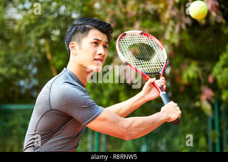 Giovani asiatici tennista di colpire la palla con una scritta Foto Stock