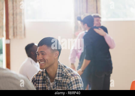 Uomo sorridente godendo di una terapia di gruppo Foto Stock