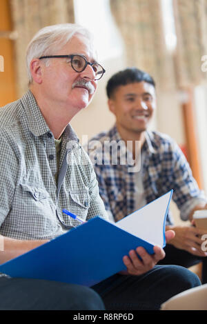 Attento uomo senior prendere appunti in riunione Foto Stock