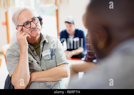 Attento uomo senior di ascolto in terapia di gruppo Foto Stock