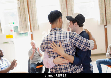 Gli uomini abbraccia in una terapia di gruppo Foto Stock