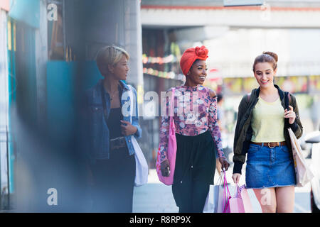 Donne giovani amici a piedi con le borse della spesa sul marciapiede urbano Foto Stock