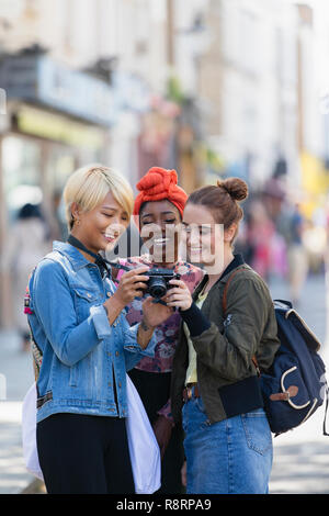 Giovani donne amici utilizzando la fotocamera digitale su strada urbana Foto Stock