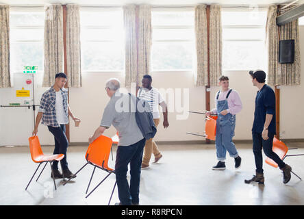 Gli uomini di disporre le sedie per la terapia di gruppo in centro nella comunità Foto Stock