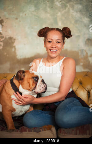 Ritratto sorridente giovane donna petting cane sul divano Foto Stock