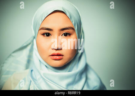 Ritratto fiduciosi, grave giovane donna indossa seta blu hijab Foto Stock