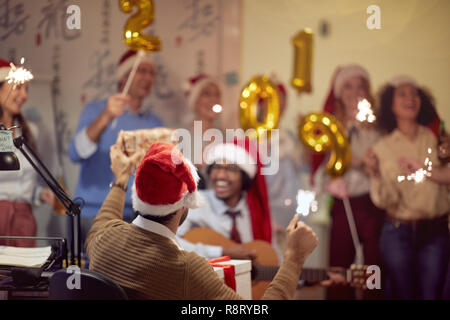 Business man in Santa pac celebra il Natale con colleghi di lavoro Foto Stock