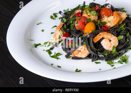 Nero Seppia Fettuccine con gamberi o gamberetti pomodori ciliegia, prezzemolo, peperoncino in vino e salsa di burro. Foto Stock