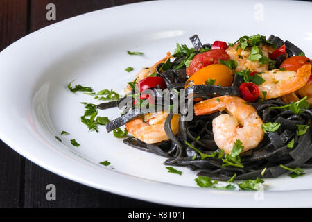 Nero Seppia Fettuccine con gamberi o gamberetti pomodori ciliegia, prezzemolo, peperoncino in vino e salsa di burro. Foto Stock