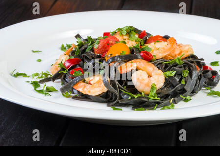 Nero Seppia Fettuccine con gamberi o gamberetti pomodori ciliegia, prezzemolo, peperoncino in vino e salsa di burro. Foto Stock