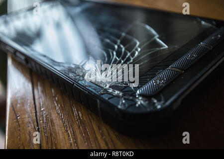 Incrinato toccare lo schermo dello smartphone su un tavolo di legno Foto Stock
