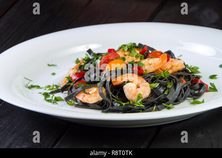 Nero Seppia Fettuccine con gamberi o gamberetti pomodori ciliegia, prezzemolo, peperoncino in vino e salsa di burro. Foto Stock