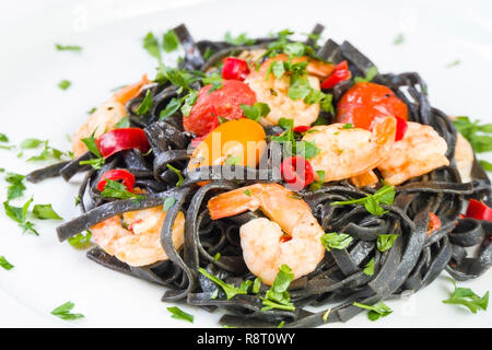 Nero Seppia Fettuccine con gamberi o gamberetti pomodori ciliegia, prezzemolo, peperoncino in vino e salsa di burro. Foto Stock