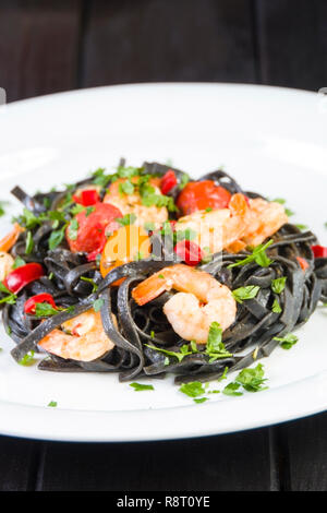 Nero Seppia Fettuccine con gamberi o gamberetti pomodori ciliegia, prezzemolo, peperoncino in vino e salsa di burro. Foto Stock