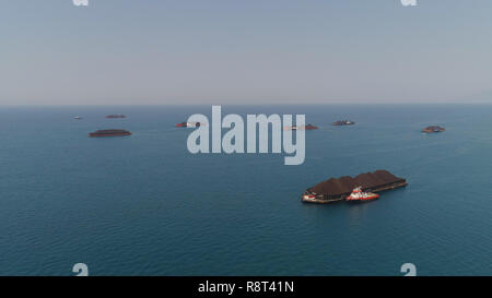 Vista aerea chiatte piena del carbone ancorato al mare nei pressi di coal fired power station in attesa di essere trasportati. carbone chiatte e rimorchiatori java, paiton indonesia Foto Stock