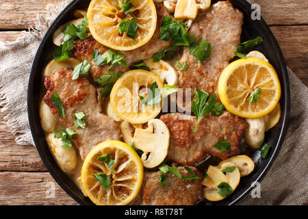 Italiano scaloppini di vitello con funghi e limoni in una salsa di close-up in una padella sul tavolo. parte superiore orizzontale vista da sopra Foto Stock