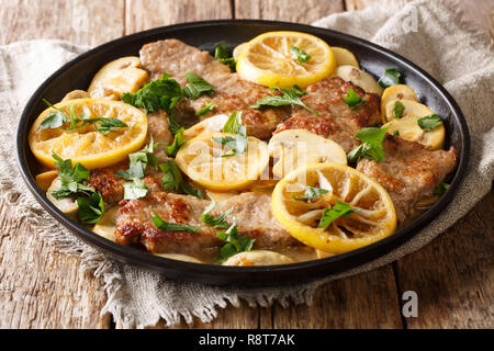 Gara Scaloppini vitello cotto con funghi e limoni in una salsa piccante di close-up in una padella sul tavolo. orizzontale, stile rustico Foto Stock
