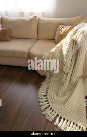 Elegante vivacemente parte del salotto con lussuosi pavimenti in legno. Invitante comodo divano con fatti a mano coperta di lana. Posizione comoda per la lettura o Foto Stock