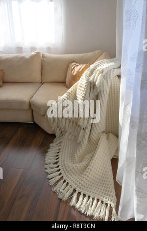 Elegante vivacemente parte del salotto con lussuosi pavimenti in legno. Invitante comodo divano con fatti a mano coperta di lana. Posizione comoda per la lettura o Foto Stock