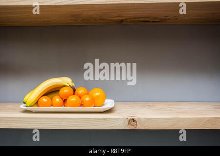 Scaffale con varie cose e frutti sul tavolo, le banane fresche e arancione Foto Stock