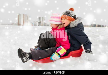 Bambini piccoli scorrevole sulla slitta giù per la collina in inverno Foto Stock