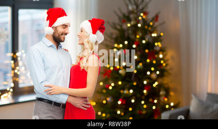 Coppia felice in cappelli di Babbo Natale abbracciando il natale Foto Stock