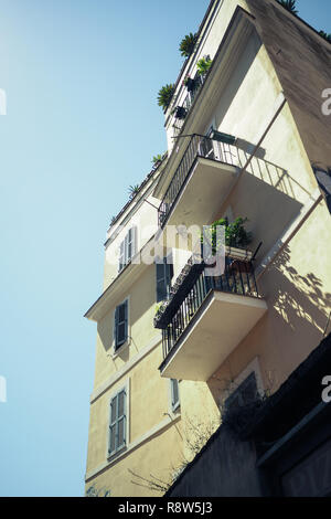 Edificio giallo con balconi e piante contro il cielo blu Foto Stock