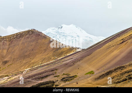 Persone escursionismo fino al Rainbow Mountain con l'Ausangate ghiacciaio in background, Perù Foto Stock