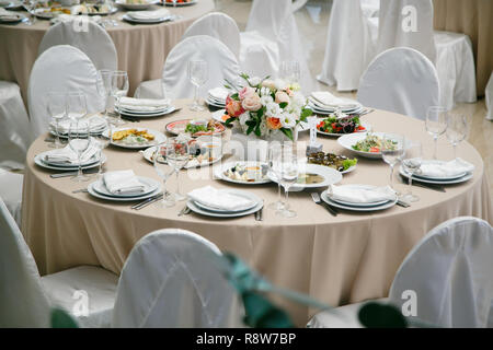 Servita per banchetti ristorante tavolo con piatti, snack, posate, vino e bicchieri di acqua. Foto Stock