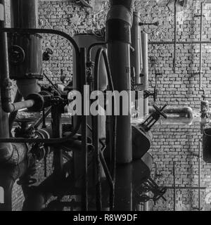 Vecchi tubi di riscaldamento specchiata in acqua in bianco e nero Foto Stock