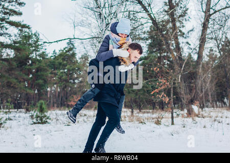 Guy dando la sua fidanzata sovrapponibile in inverno foresta. Giovani amare giovane avendo divertimento all'aperto. Le persone felici rilassante Foto Stock