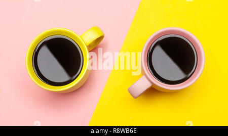 Lay piatto vista dall'alto di due tazze da caffè con rosa e giallo. Foto Stock