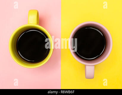 Lay piatto vista dall'alto di due tazze da caffè con rosa e giallo. Foto Stock