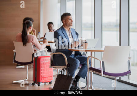 Imprenditore pensieroso a guardare fuori dalla finestra in aeroporto business lounge Foto Stock