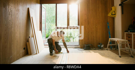 Operaio edile di misura scheda di legno in casa Foto Stock