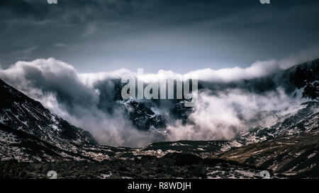 Le nuvole si estendesse una cresta di montagna Foto Stock