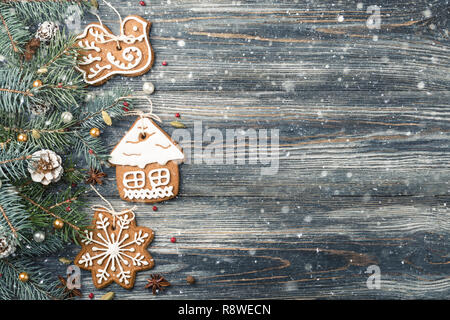 Telaio di natale di Gingerbread cookie e decorazioni su abete rosso su innevate sullo sfondo di legno, copia dello spazio. Foto Stock