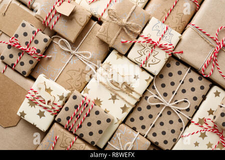 Sfondo di natale con molti fatti in casa decorativi confezioni regalo avvolto in marrone carta kraft. Rosso Bianco spago. Lay piatto. Foto Stock