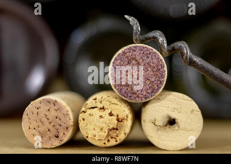 Un cavatappi per la stappatura vino e vecchi tappi su di un tavolo di legno. Vino vecchio accessori. Sfondo chiaro. Foto Stock