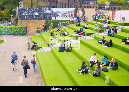 London, Regno Unito - Ottobre 2017: Giovani studenti seduti all'aperto in Piazza granaio passi. Granary Square è una piazza pubblica sulle rive del Regent's C Foto Stock