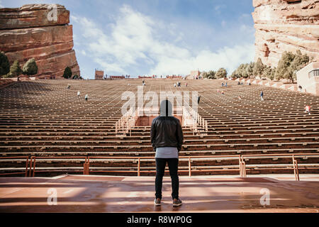Ritratto simmetrica di persona in piedi su un palco di sognare mentre di fronte si erge Stadium posti a sedere presso l'anfiteatro all'aperto Concert Music Hall al di fuori Foto Stock